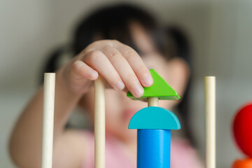 Close-up of 3 year old girl's hands having fun playing with colorful geometric shape wooden blocks...