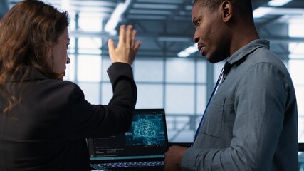 Software developers using AI tech on laptop in data center managing server virtualization. IT expert coding on notebook in server room using artificial intelligence, finetuning network, camera A