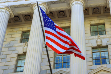Bright sunlight illuminates American flag flying proudly outside classic architectural structure at Washington D.C
