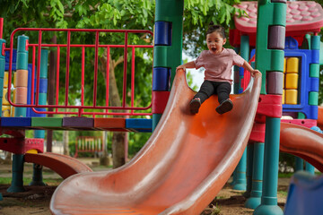 happy toddler baby girl sliding and playing at playground