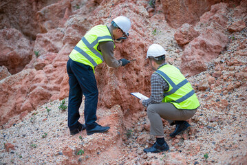 Expert geologists are working together to analyze rock layers in a mountain to study the minerals...