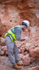 A geologist is examining minerals in the layers of rock on a mountain.