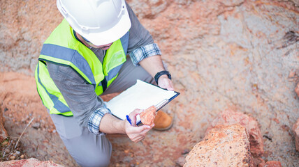 A geologist is examining minerals in the layers of rock on a mountain.