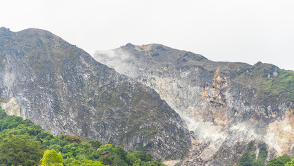 Steam rises from the rugged slopes of Mount Sibayak, a volcanic peak surrounded by lush tropical...