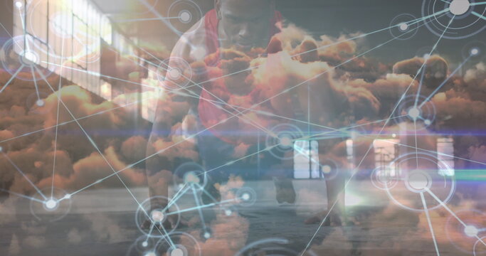 Network of digital icons over clouds in the sky against african american fit man performing push ups