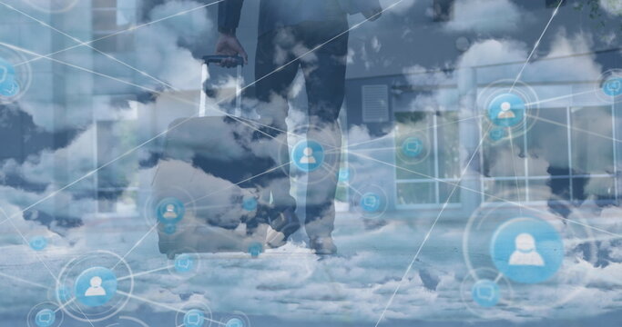 Image of network of profile icons over clouds against businessman walking with a trolley bag