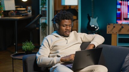 Freelancer listening to a podcast and being focused on online work, putting on headphones while...