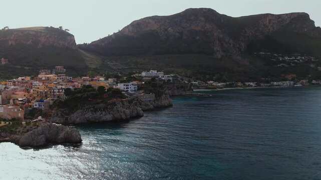 Aerial 4K footage of Porticello coastal village in Sicily Italy showing colorful houses on rocky cliffs turquoise sea Monte Catalfano and the coastline stretching toward Aspra and Bagheria