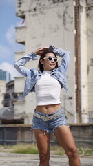 Young Asian woman in urban environment in a stylish summer outfit, featuring ripped denim shorts, a...