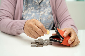 Asian senior or elderly old lady woman holding counting coin money in bag. Poverty, saving problem in retirement.
