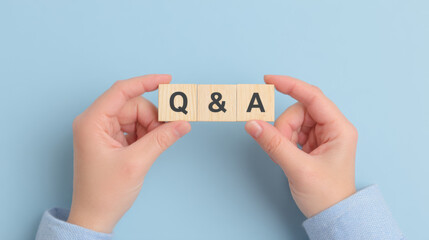 A pair of hands are holding two wooden blocks, Q and A, symbolizing the solution to the problem
