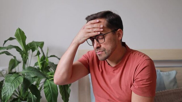 Man touches forehead and head due to headache, feeling unwell, blood pressure