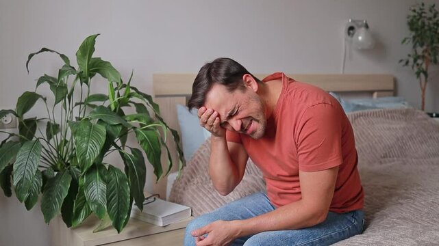 Sad Man touches his head because of headache or emotional distress. Grief and depression.