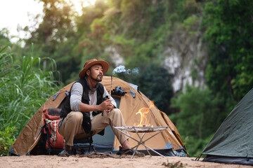 Man relax in front of his tent, look at the dry branches that the fire has extinguished and turned...