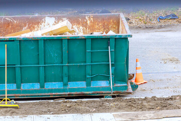 Workers dispose of construction waste in large container located on construction site suburban...