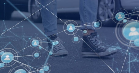 Image of network of digital icons against low section of man walking on the street
