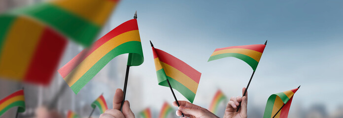 Bolivia flags in their hands on a blurred urban background