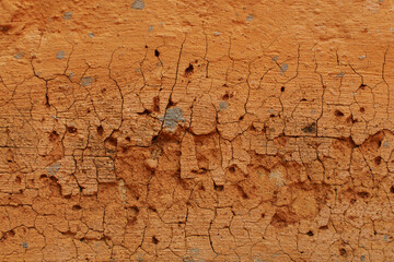 Close-up photo of cracked orange painted cement surface.