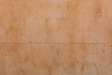 Close-up photo of cracked orange painted cement surface.