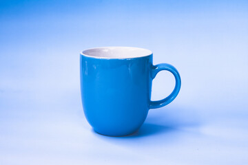 Vibrant blue drinking cup with smooth finish sits against matching blue background, creating harmonious and calming visual effect