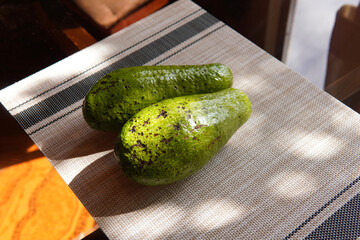 Two avocados on a wooden and glass table with a rustic and country background