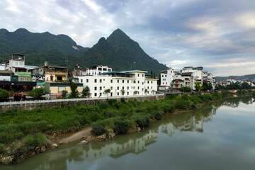 Obraz premium Ha Giang town stretching along the river with forested mountains in the background