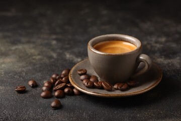 Fototapeta premium Coffee cup and coffee beans on dark background, closeup
