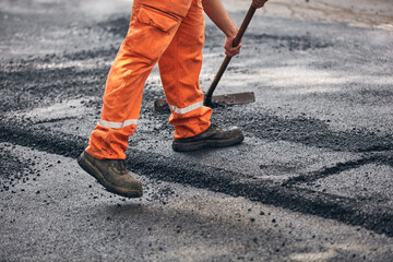 Fototapeta na wymiar Construction worker working on a new asphalt layer on a public street.