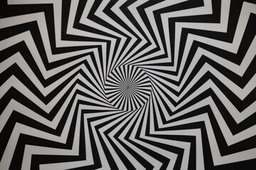 High-contrast black and white zigzag lines form a hypnotic spiral pattern.