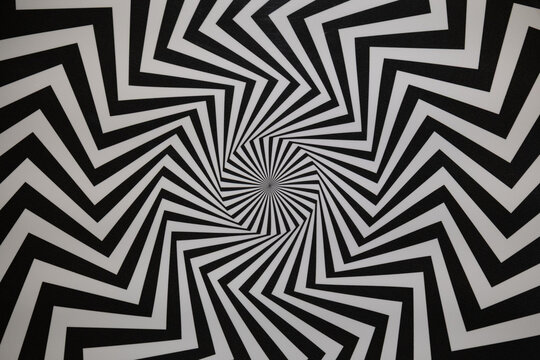 High-contrast black and white zigzag lines form a hypnotic spiral pattern.