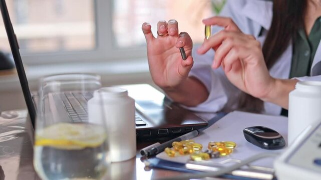 Close-up Doctor showing dark and transparent yellow oval capsules and pills. Alternative medicine, Dietary supplements, Vitamins and minerals