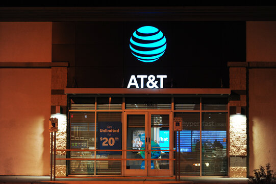 AT&T retail store features illuminated signage and window ads promoting wireless plans and fiber internet, representing a major provider of mobile, broadband, and entertainment services