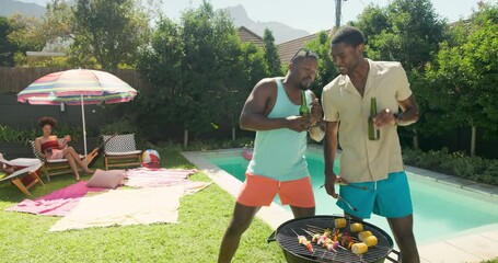 Diverse friends enjoying barbecue by pool, dancing and laughing on sunny day