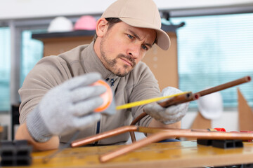 young plumber measuring copper pipe