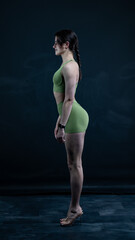 Fototapeta premium Young beautiful woman with athletic body on dark background. Fitness girl 