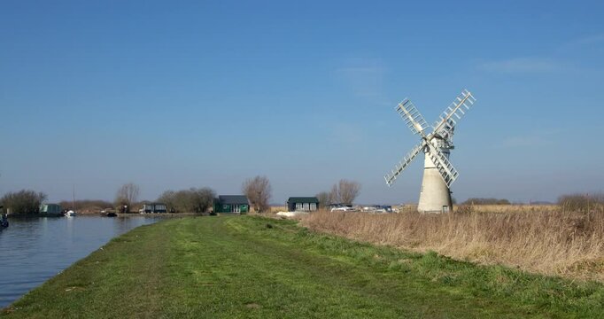 Long shot looking down a inlet on the river Thurne at the village of Thurne, with Thurne mill in background.