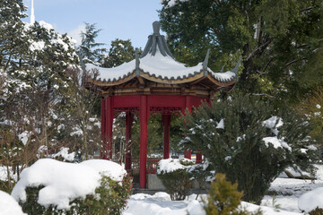 Gazebo-pagoda covered with snow in a Japanese garden-style urban park