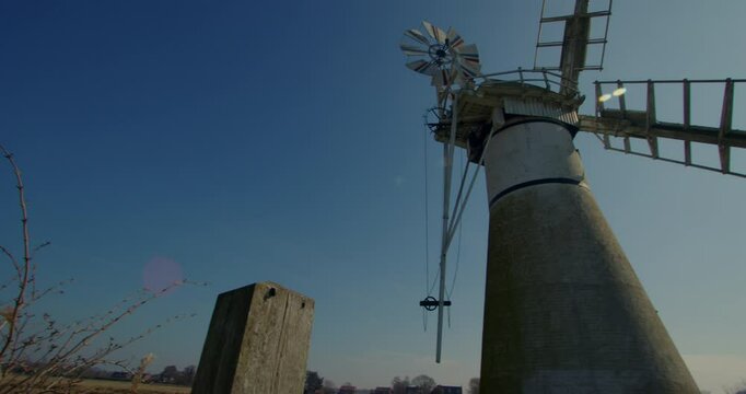 panning shot looking up Thurne mill ending in silhouette with sun in background