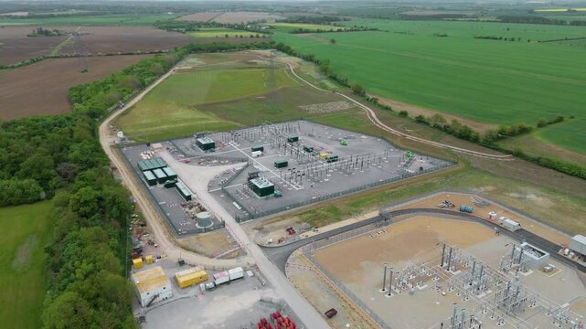 Aerial drone footage of the Biggleswade electric substation in England, UK. The scene captures power pylons, terminals, and energy infrastructure