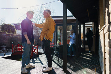 Father and son bonding in the backyard with family nearby