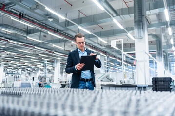 Employee in a production hall taking notes on a clipboard