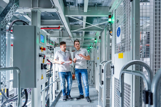 Employees discussing notes on a tablet in a production hall