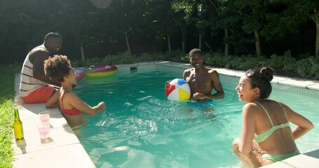 Diverse friends enjoying pool party, splashing water and playing with beach ball outdoors - Powered by Adobe