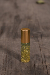 Small bottle of perfume with real gold flakes on wooden pad