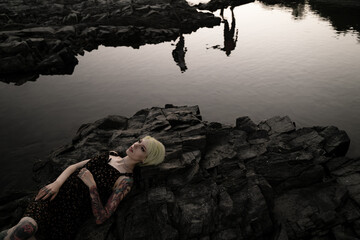 A woman lies on a rock in the middle of the water enjoying nature