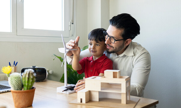Male architect and boy touching wind turbine model at home office