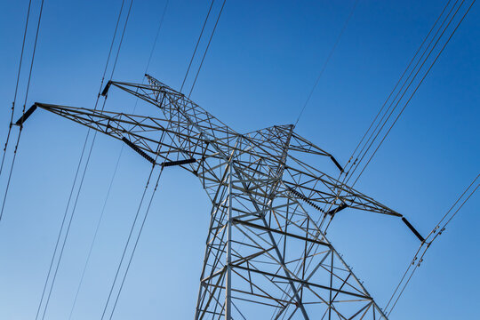 Dynamic diagonal view of electrical pylon and high voltage lines under a clear blue sky
