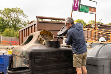 Man pouring engine oil into container in recycling centre.