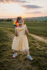 Little girl playing with windmill at sunset