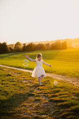 Little girl having fun with soap bubbles in the field